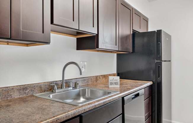 A kitchen with brown cabinets and a black refrigerator.