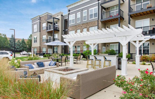 A patio with a white pergola and a planter box is surrounded by apartment buildings.
