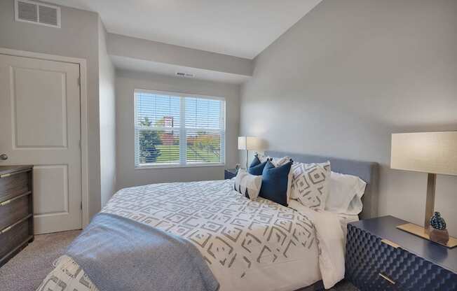 A bedroom with a large bed and a window with blinds.