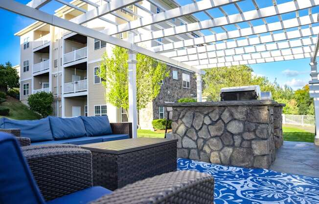 a covered patio with furniture and a stone fireplace