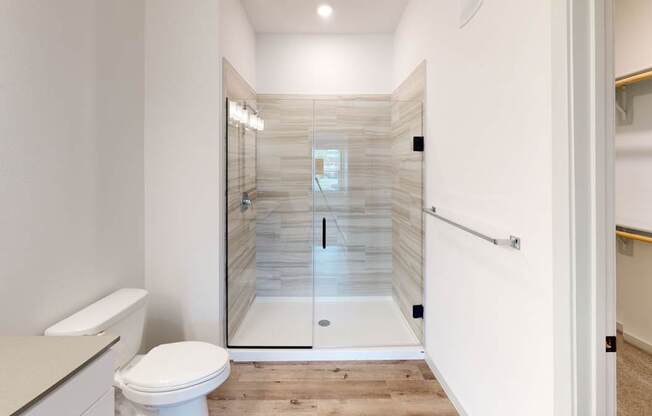 A white toilet is in a bathroom with a walk-in shower.