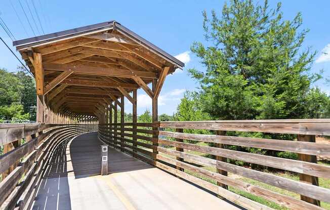 A covered wooden bridge with railing that leads to the Beltline and Bobby Jones Golf Course.