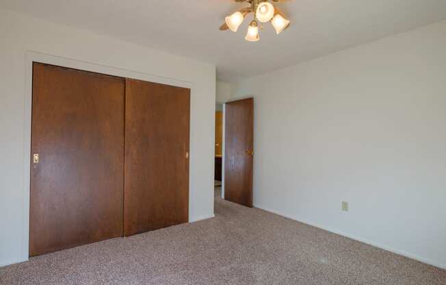 a bedroom with a closet and a ceiling fan. Fargo, ND Country Club Apartments.