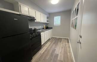 a kitchen with a black refrigerator freezer next to a stove top oven at The Junction, Tennessee, 38111