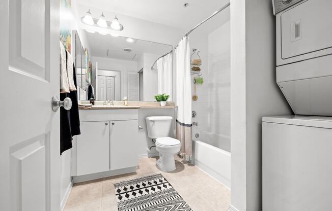 a small bathroom with a white washer and dryer next to a toilet