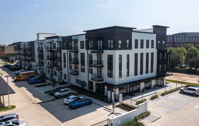 A modern apartment complex with a parking lot in front.