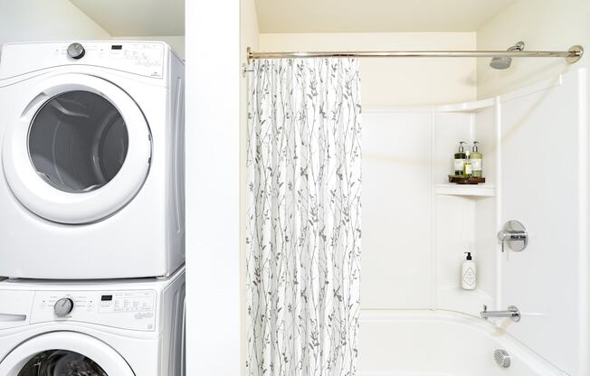 A white washing machine and dryer stacked on top of each other in a laundry room.