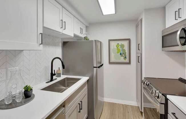 A kitchen with white cabinets and a grey backsplash.