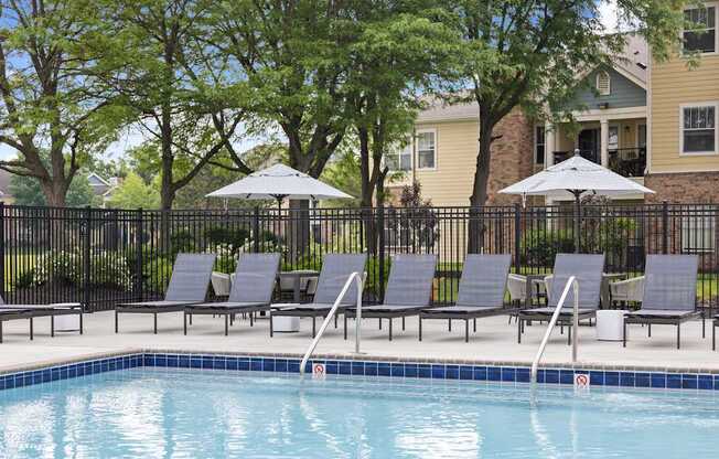 Shaded poolside seating area with loungers and umbrellas at Center Point Apartments offering a peaceful spot to relax outdoors.