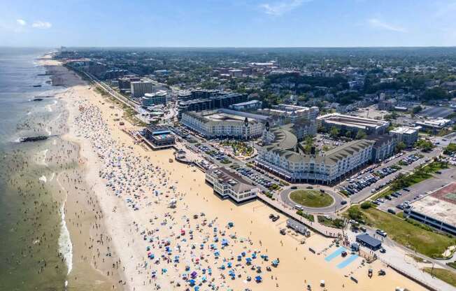 A crowded beach with people and umbrellas under a clear sky.