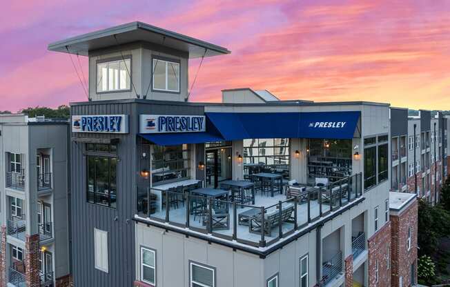 the facade of a building with tables and chairs at sunset