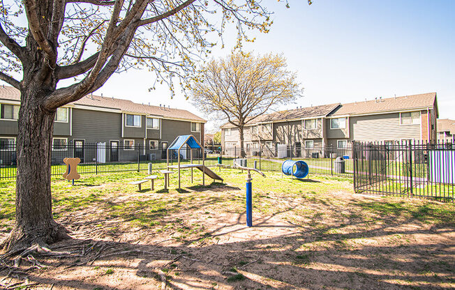 A playground area with a swing set and a slide in front of apartment buildings.