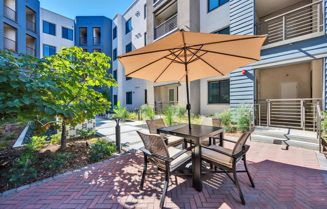 A patio with a table and chairs under an umbrella.
