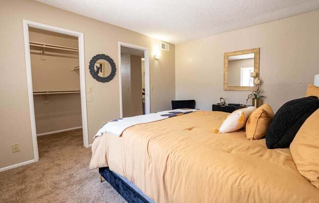 A bedroom with a bed, dresser, mirror, and wardrobe.