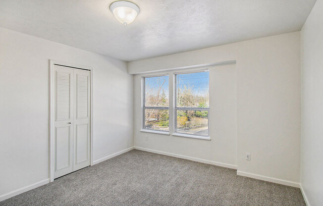 Bedroom with a large window and a walk in closet at Canal 2 Apartments, Lansing, Michigan