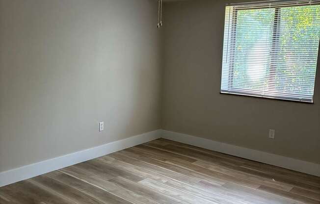 A room with a ceiling fan and a window with blinds.