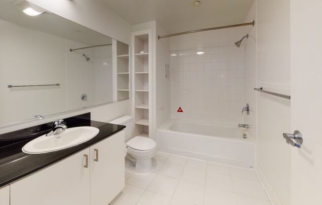 a bathroom with a white bathtub and a white sink with a black countertop