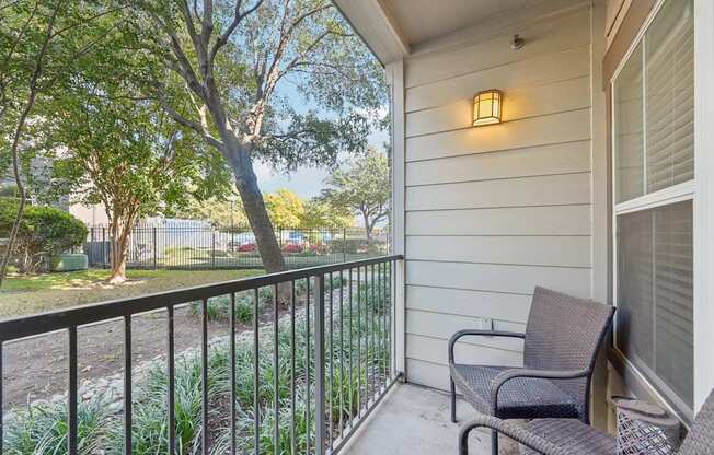 A balcony with a chair and a lamp on the wall.