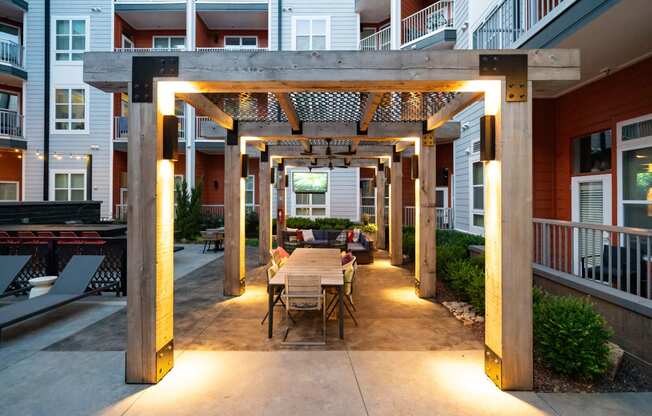 an outdoor dining area with a wooden table and chairs under a wooden pergola  at Abberly Noda Vista Apartment Homes, Charlotte, NC