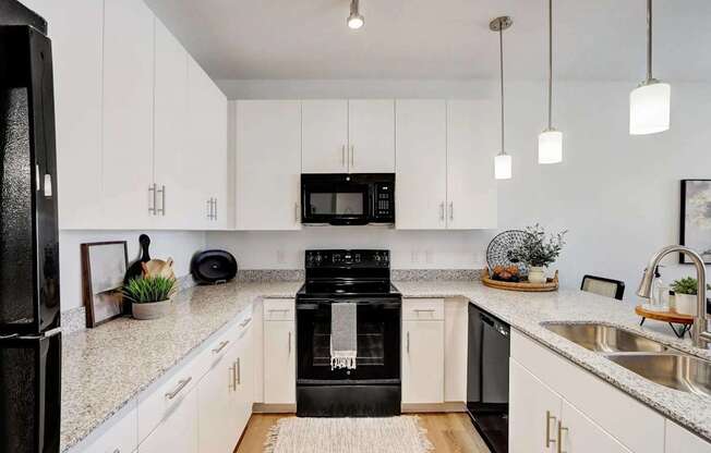 A black refrigerator is in a kitchen with white cabinets.