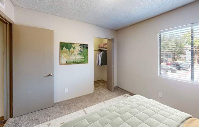 A bedroom with a bed, a painting, and a window.