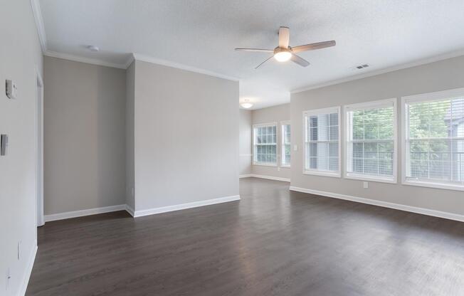 Empty room with a ceiling fan and large windows.