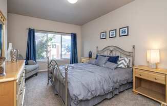 A bedroom with a large bed and a window with blue curtains.