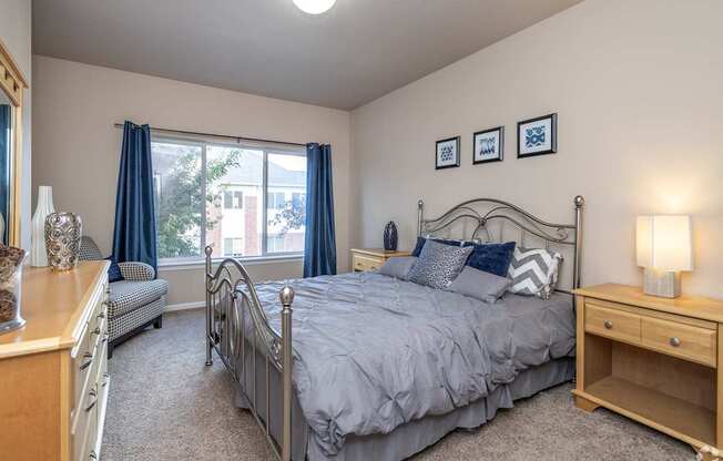 A bedroom with a large bed and a window with blue curtains.
