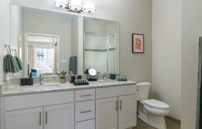 a bathroom with white cabinets and a large mirror