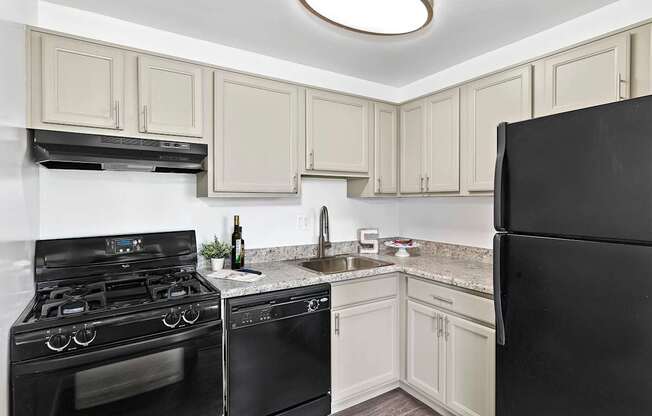 A kitchen with black appliances and white cabinets.