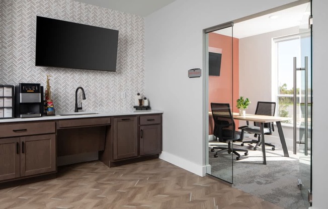 A modern kitchen with a wooden counter and a flat screen TV mounted on the wall.