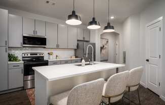 a kitchen with white cabinets and a white island with four chairs