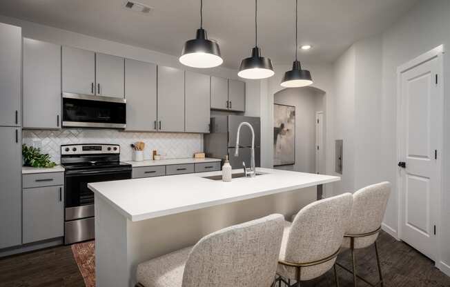 a kitchen with white cabinets and a white island with four chairs