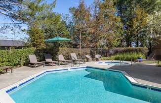 a swimming pool with chairs and a poolside umbrella