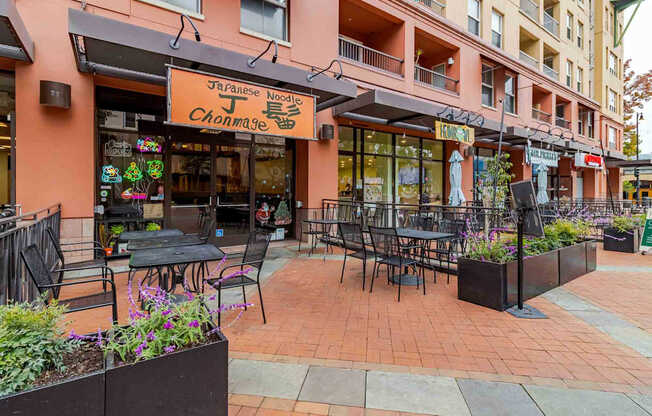 A Japanese restaurant with a red awning and tables outside.