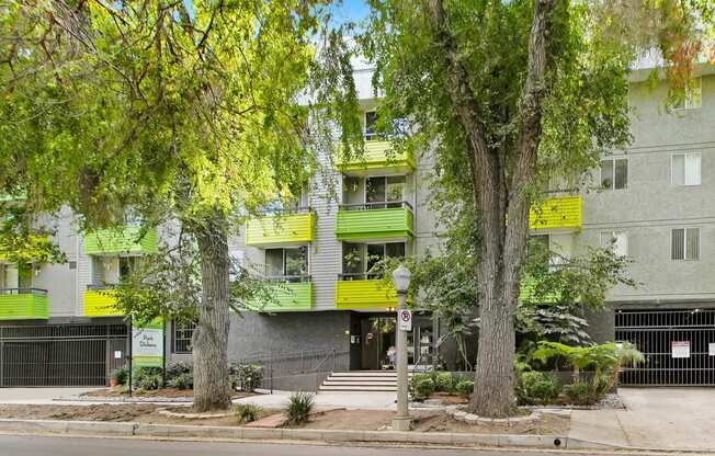 a building with green balconies and trees in front of it