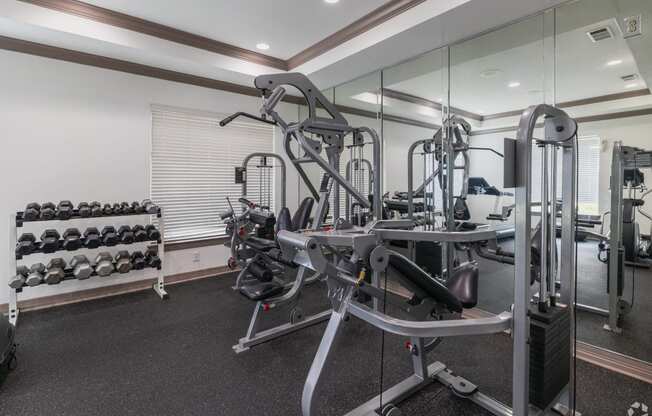 a gym with weights and cardio equipment in a building with glass walls