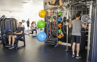 A man is working out in a gym with various exercise equipment.
