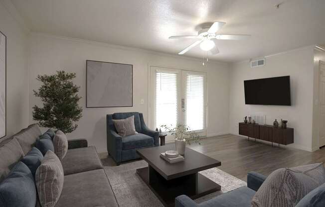 A living room with a grey couch, a blue chair, a coffee table, and a flat screen TV mounted on the wall.