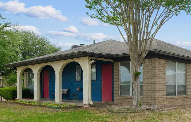 Leasing office with a red door and a tree in front.