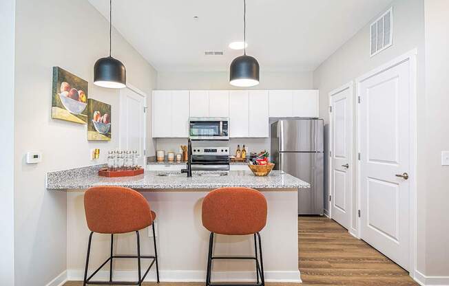A kitchen with a white countertop and orange barstools.
