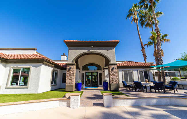 a picture of the front of the clubhouse with a blue sky and palm trees in the background