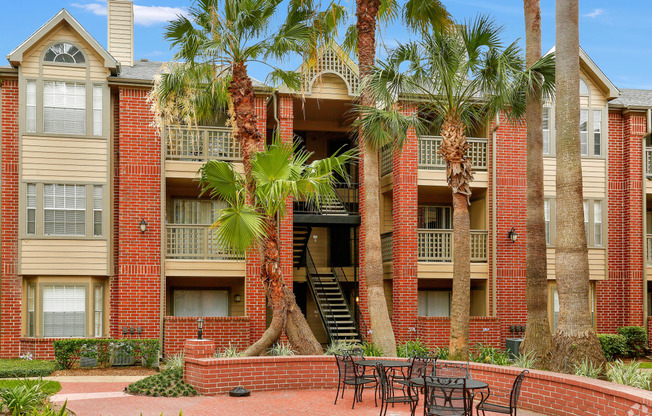 a courtyard with tables and chairs in front of an apartment building