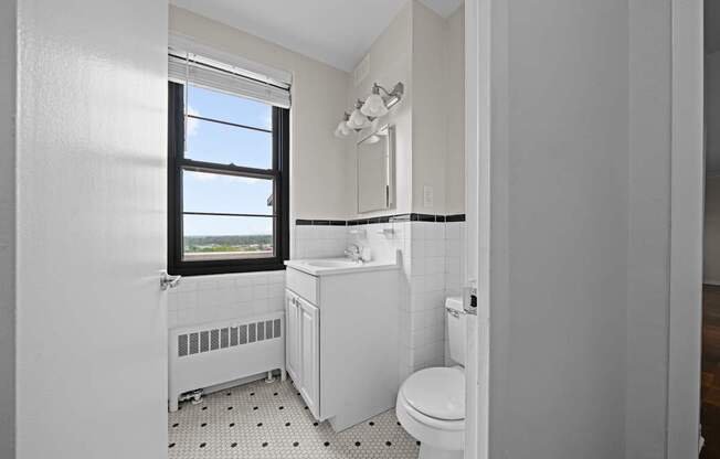 A white bathroom with a toilet, sink, and window.