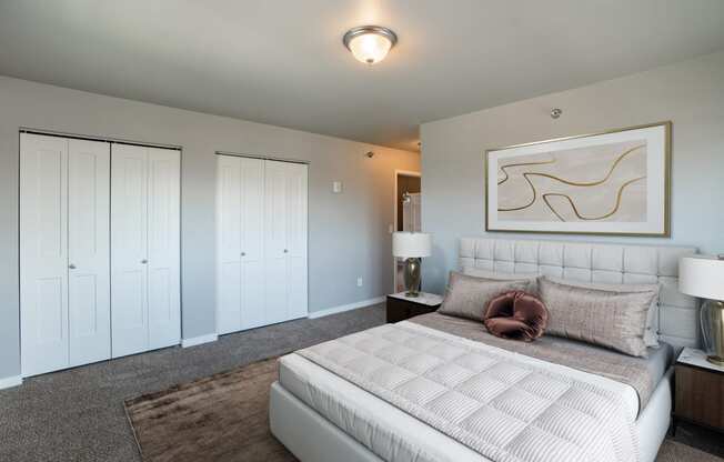 a bedroom with a large white bed and white closets. Fargo, ND 29 West Apartments