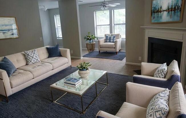 A living room with a beige couch, a glass coffee table, and a fireplace.
