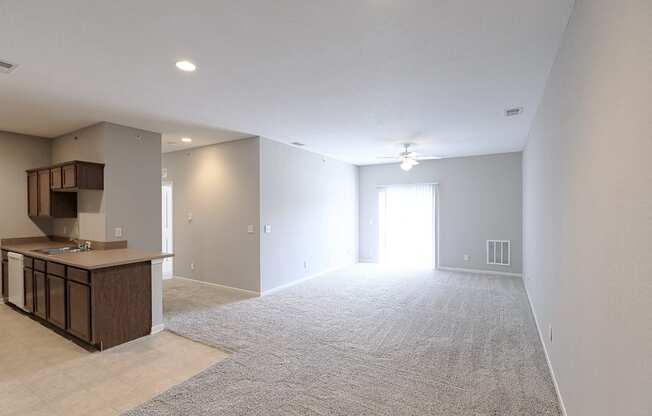 an empty living room and kitchen with an open door to the bedroom