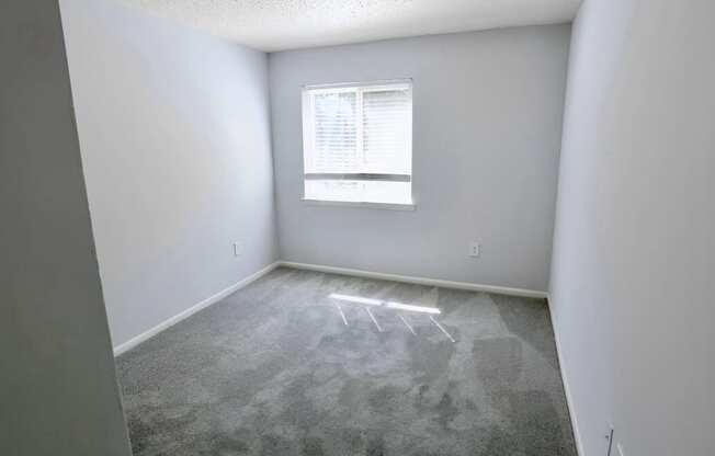 an empty room with a window and white walls