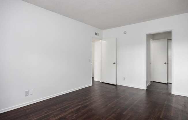 an empty living room with wood floors and white walls