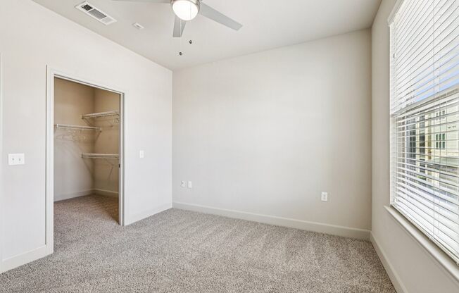 A room with a ceiling fan and a doorway leading to another room.